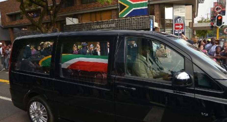 The funeral cortege of South African former president Nelson Mandela drives through the streets in Pretoria on December 11, 2013 to the Union Buildings to mark the start of a three-day lying in state.  By Filippo Monteforte AFP