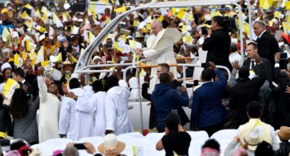 Many of the faithful wore pope-emblazoned white and yellow caps -- the colours of the Vatican, and cheered as the pope-mobile made its way through wind-swept clouds of red dust.  By Tiziana FABI AFP