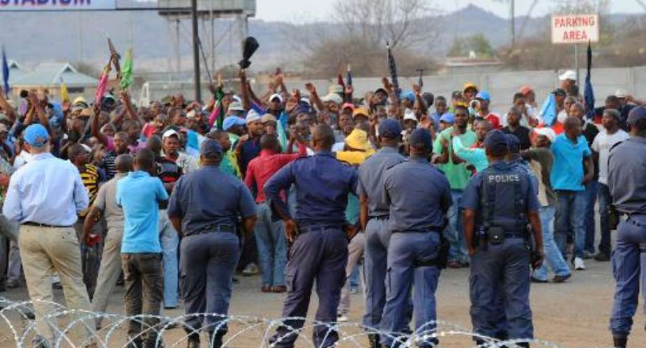 Police stand by as striking miners celebrate securing a 22 percent pay hike from London-listed Lonmin platinum mine in Marikana on September 18, 2012.  By Alexander Joe AFPFile