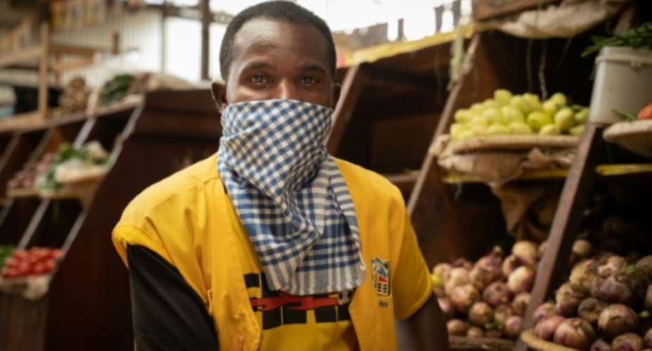 Masked: A phone credit salesman wears a dishcloth to cover his face at Kaveza market in Kigila. The country is in lockdown, and only essential stores are open..  By Simon Wohlfahrt AFP