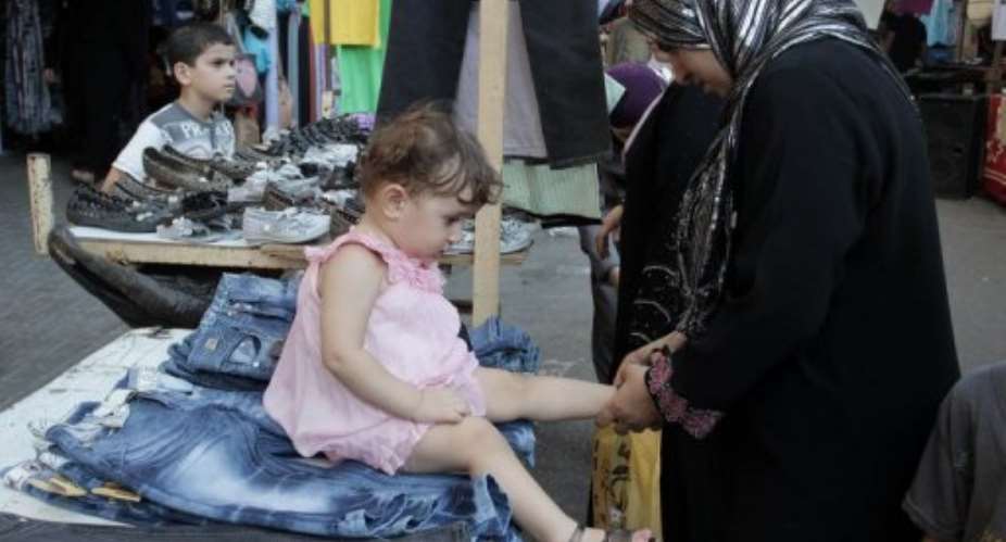 Palestinian women buy new clothes for their children ahead of the Eid al-Fitr holiday.  By Said Khatib AFP