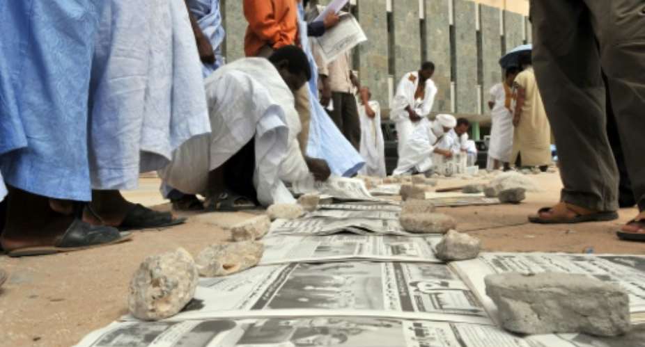Mauritanians read newspapers on a main street in Nouakchott.  By GEORGES GOBET AFPFile