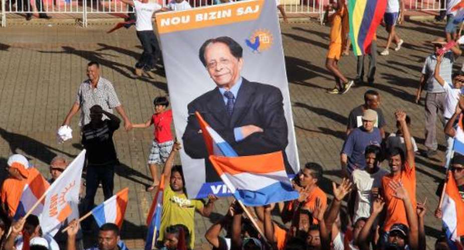Supporters of the centre-right coalition Alliance Lepep hold a poster of the coalitions leader, former president Anerood Jugnauth in Riviere du Rempart, Mauritius, December 11, 2014.  By Nicholas Larche (AFP)