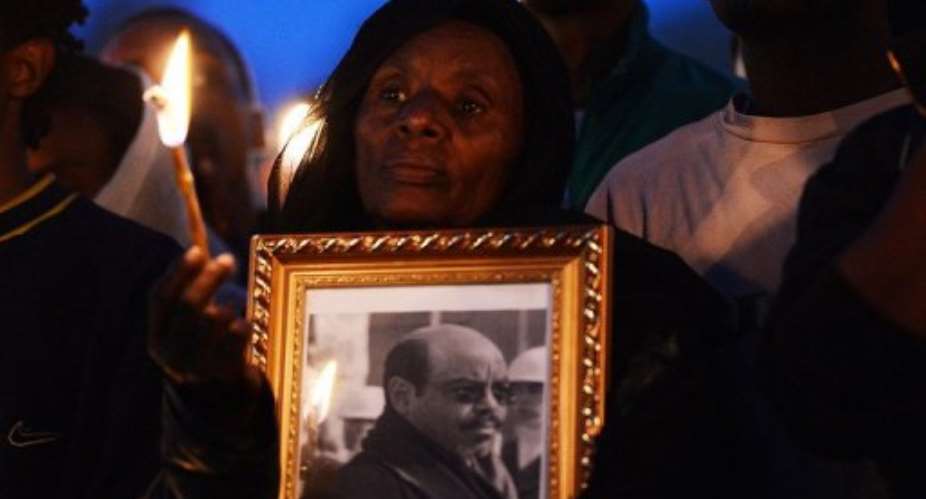 A mourner holds a candle and a portrait of late Zenawi during a candle lit vigil in Meskel square, in Addis Ababa.  By Carl de Souza AFPFile