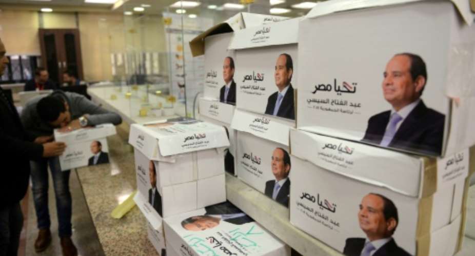Members of Egyptian President Abdel Fattah al-Sisi's presidential campaign staff stand next to boxes containing signatures in his support, needed to register for the elections, at the National Election Authority, in Cairo on January 24, 2018.  By MOHAMED EL-SHAHED AFPFile