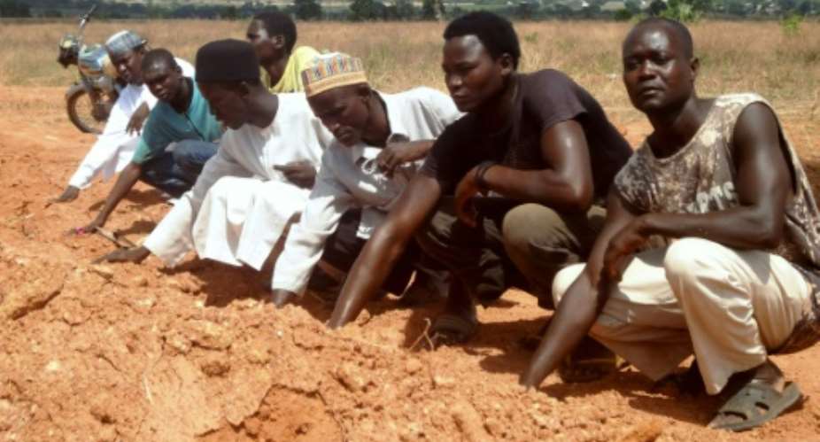 Members of the Islamic Movement of Nigeria, a Shiite group, pray at a mass grave in which 300 members of the organisation are said to be buried.  By AMINU ABUBAKAR AFPFile
