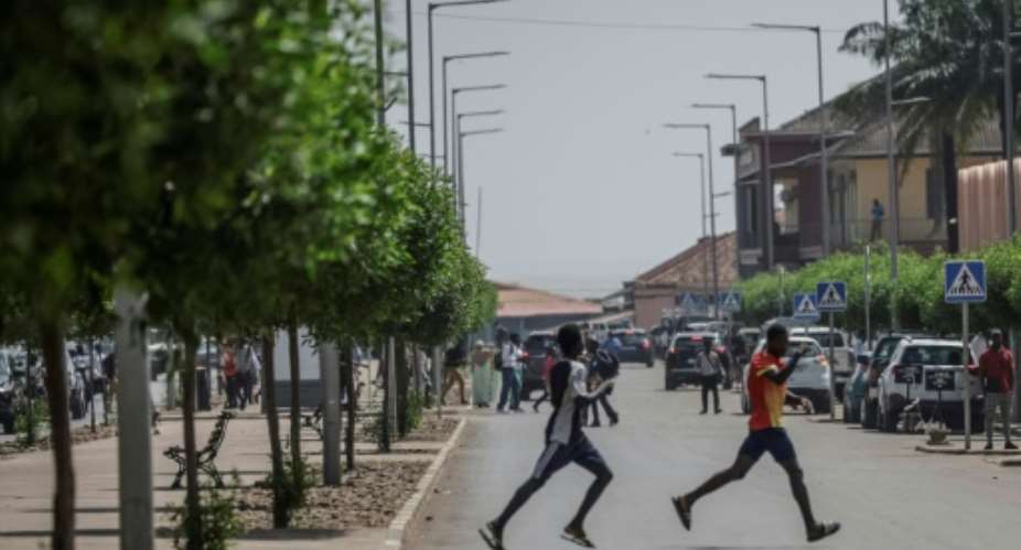 Men flee the scene as gunfire rings out near the presidential palace in Bissau on November 26, 2025.  By Patrick MEINHARDT (AFP)
