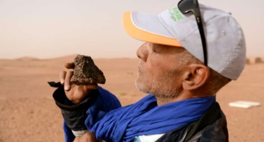 Meteorite hunter Mohamed Bouzgarine examines a rock near the town of M'hamid el-Ghizlane, in southern Morocco..  By FADEL SENNA AFP