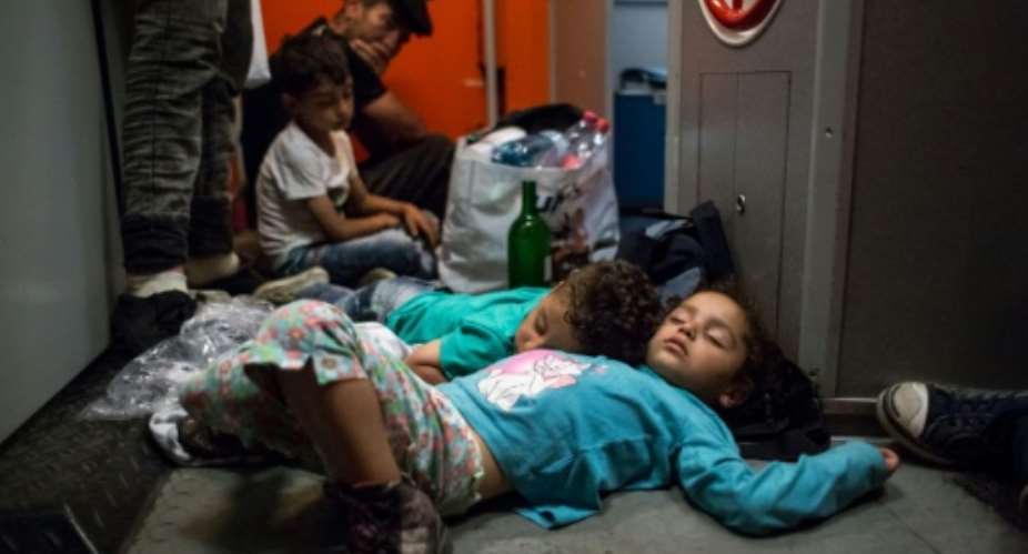 Migrant children sleep on the floor on the train from Budapest to Munich at the Austrian - Hungarian border in Hegyeshalom on August 31, 2015.  By Vladimir Simicek AFP