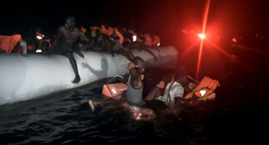Migrants and refugees wait to be rescued from their sinking rubber boat some eight nautical miles off Libyas Mediterranean coastline on October 12, 2016.  By Aris Messinis (AFP)