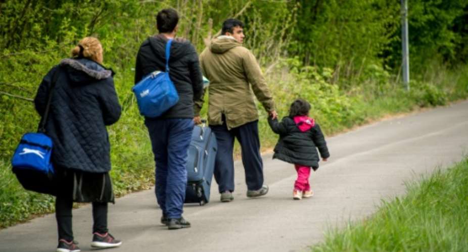 Migrants are seen walking in northern France in 2017, the y ear after the UN says people-smuggling rings earned some 7 billion -- an amount equal to US and EU humanitarian aid that year.  By PHILIPPE HUGUEN AFPFile