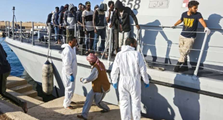 Migrants disembark in October 2019 from a Libyan coast guard ship in the town of Khoms, part of the instability that has led the United States to impose sanctions on smugglers.  By Mahmud TURKIA AFPFile