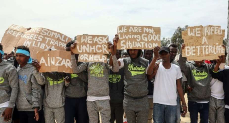 Migrants hold placards during United Nations Secretary-General Antonio Guterres unseen visit to Ain Zara detention centre for migrants in the Libyan capital Tripoli on April 4, 2019.  By Mahmud TURKIA AFPFile