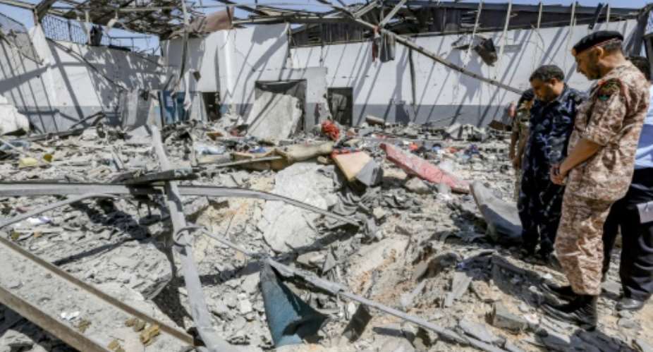 Military officers of the Libyan Government of National Accord GNAinspect damage at a migrant detention center in the capital Tripoli's southern suburb of Tajoura on July 3, 2019, following an air strike on a nearby building that left dozens killed.  By Mahmud TURKIA AFP