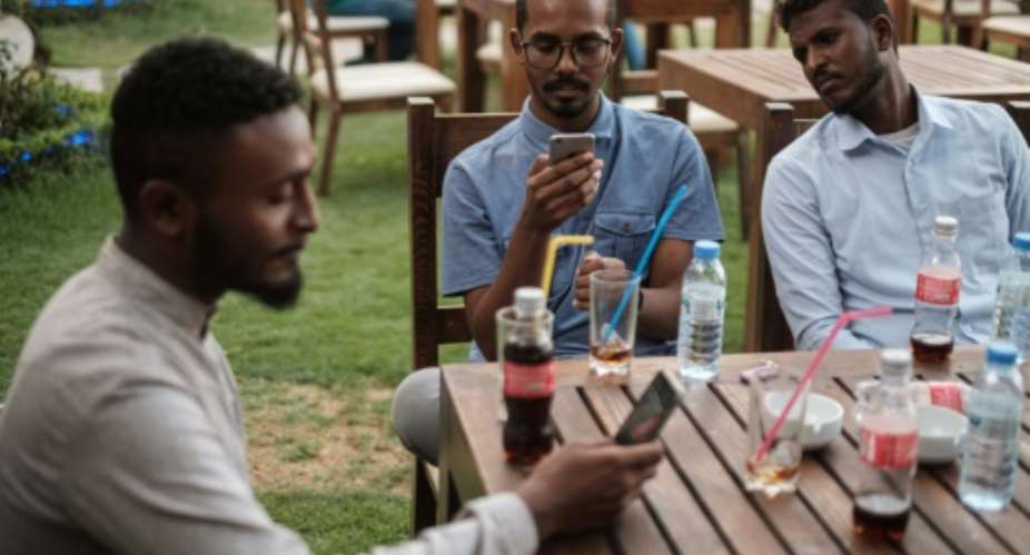 Mohamed Omar L sits with his friends at a cafe in an upscale district of Sudan's capital on June 17, 2019.  By Yasuyoshi CHIBA AFP