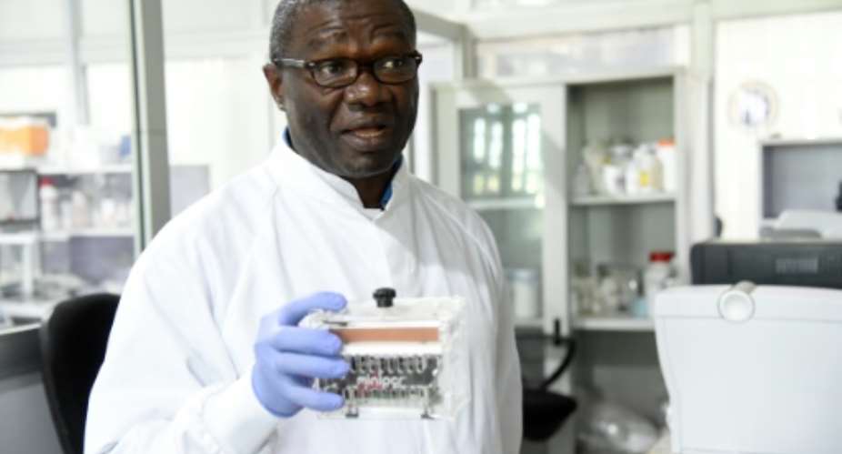 Molecular biologist Christian Happi, head of the ACEGID genomics lab, holds a thermal cycler, which amplifies genetic segments of the virus.  By PIUS UTOMI EKPEI AFP