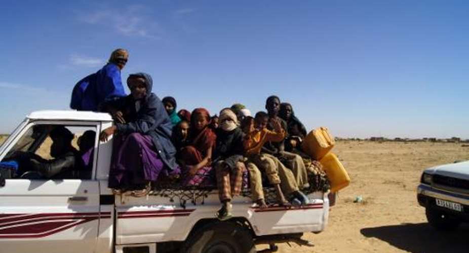 Malian refugees ride in the back of a truck transporting them on a dirt road from Timbuktu to the Mauritanian town of Fassala on January 18, 2013.  By - Al-Akhbar News AgencyAFPFile