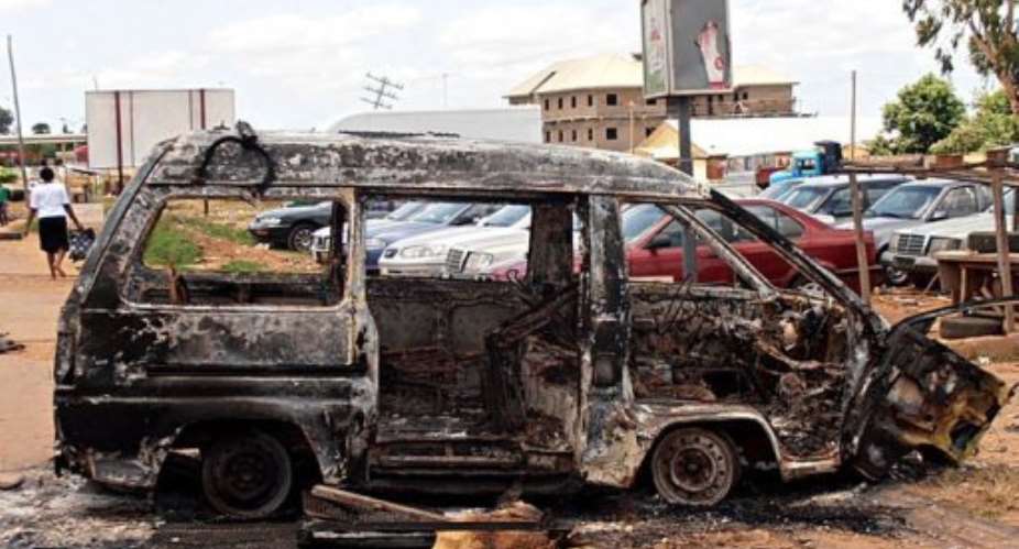 A woman walks near a minibus burnt by an angry mob in reaction to suicide bomb attacks.  By Victor Ulasi (AFP)
