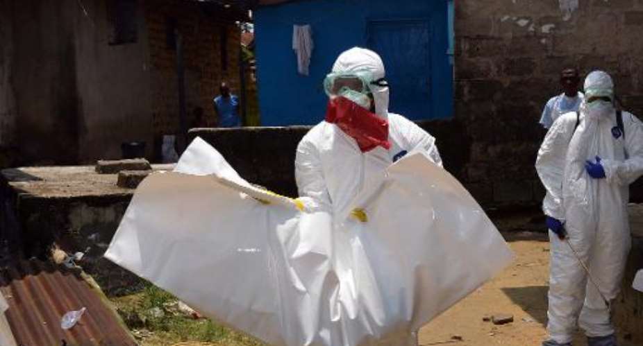 Liberian Red Cross health workers, wearing protective suits, carry the body of a 18-old-month baby, victim of the Ebola virus on September 12, 2014.  By Zoom Dosso AFPFile