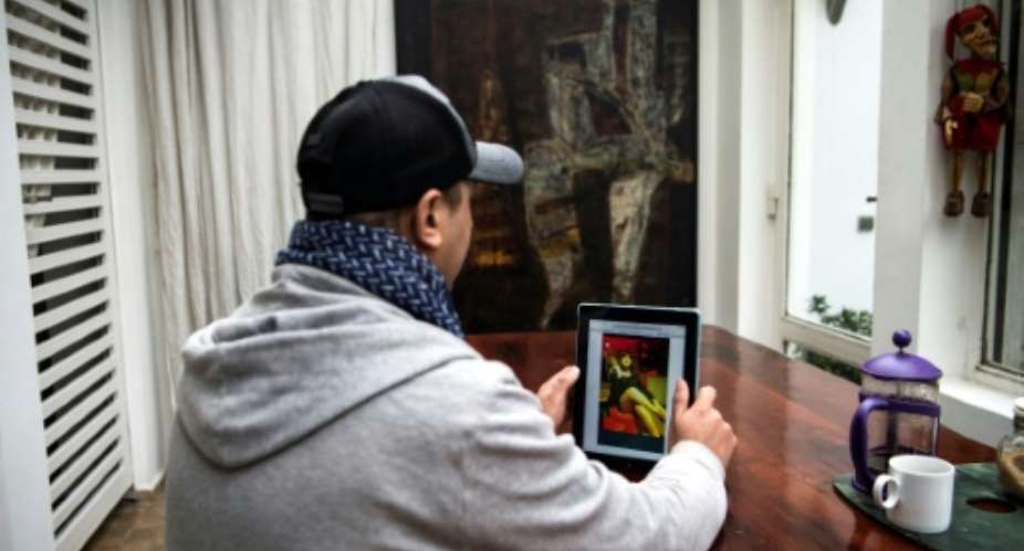 Moroccan Chafik Lafrid looks at a picture of himself on a tablet which went viral, taken after his arrest wearing a dress and a wig.  By FADEL SENNA (AFP)