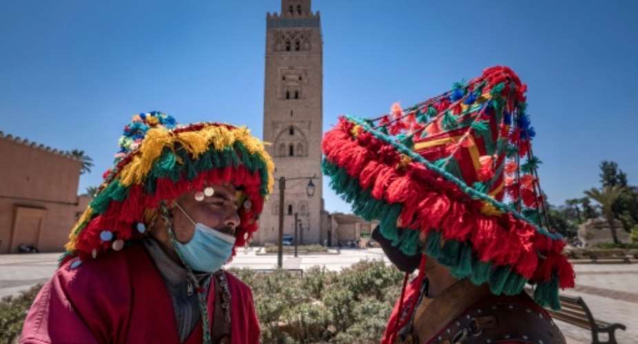Moroccan water sellers, who have been impacted by the Covid-19 crisis since its start due to the scarcity of tourism, chat in front of the Koutoubia mosque in the city of Marrakesh.  By FADEL SENNA AFP
