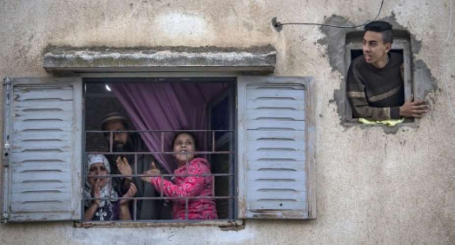 Moroccans confined at home thank the authorities from their windows as security forces and health workers instruct people to return to and remain at home as a measure against the COVID-19 coronavirus pandemic, in Rabat's district of Takadoum.  By FADEL SENNA AFP