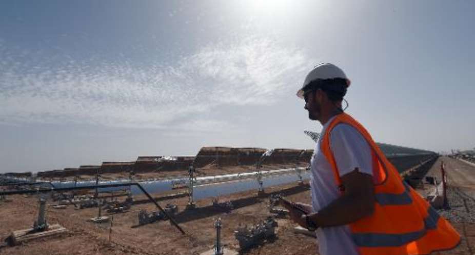 A worker stands in front of a solar array that is part of the Noor 1 solar power  project in Ouarzazate on October 19, 2014.  By Fadel Senna AFPFile