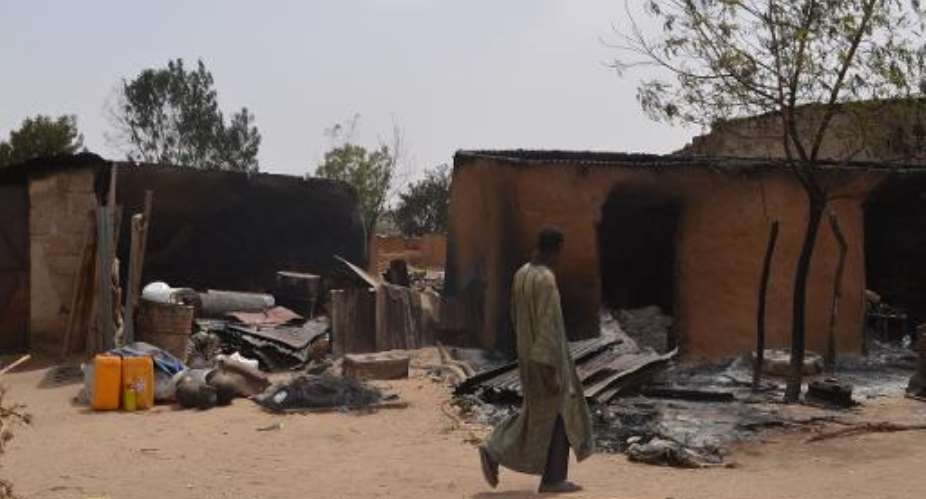 A villager walks past razed homes in Mainok, outside Maiduguri in Borno State on March 6, 2014.  By  AFPFile