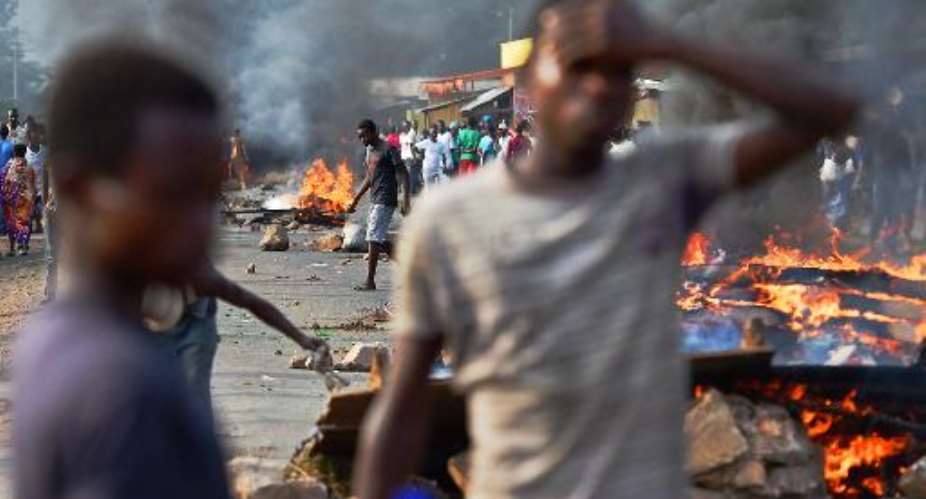 Protestors stands near a burning barricade during a demonstration against President Pierre Nkurunziza's bid for a third term, in the Cibitoke neighborhood of Bujumbura on May 22, 2015.  By Carl de Souza AFPFile
