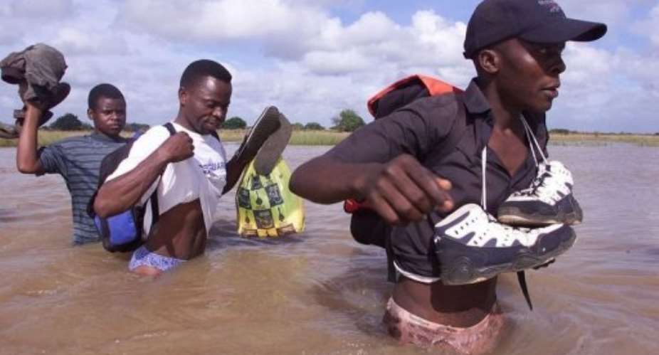 Mozambicans cross a flooded area close to Palmeria on February 25, 2000.  By Yoav Lemmer AFPFile