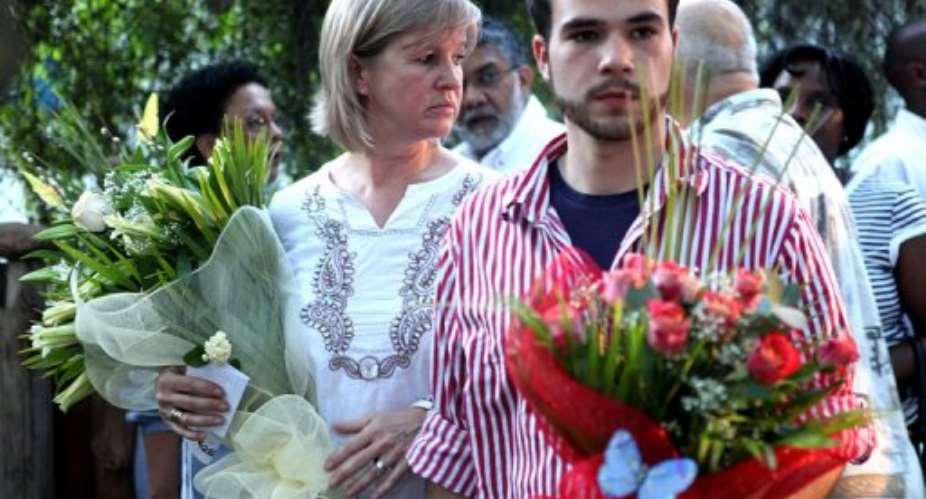 Nina Berg, the widow right and son of Carlos Cardoso carry flowers at his monument in Maputo, November 22, 2010.  By Benoit Marquet AFPFile