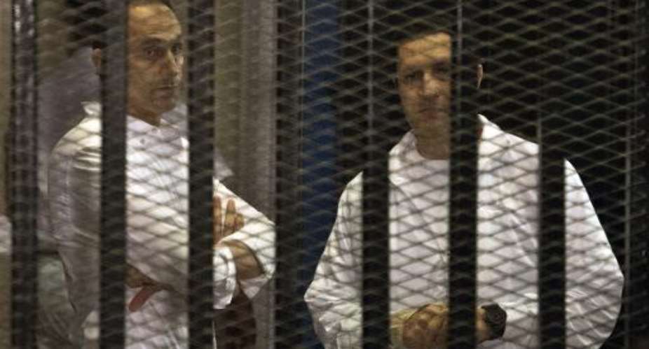 Sons of ousted Egyptian president Hosni Mubarak, Gamal L and Alaa behind the defendants' cage during their retrial at the Police Academy in Cairo, on June 8, 2013.  By Khaled Desouki AFPFile