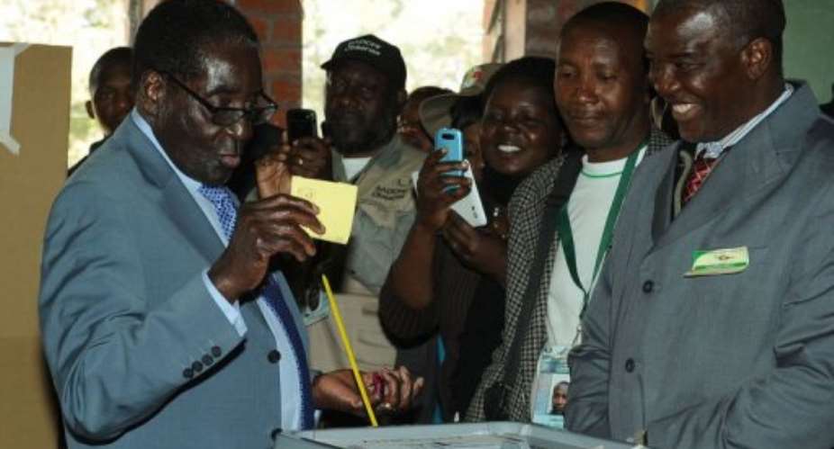Zimbabwe President Robert Mugabe L casts his vote at a polling booth in a school in Harare on July 31, 2013.  By Alexander Joe AFP