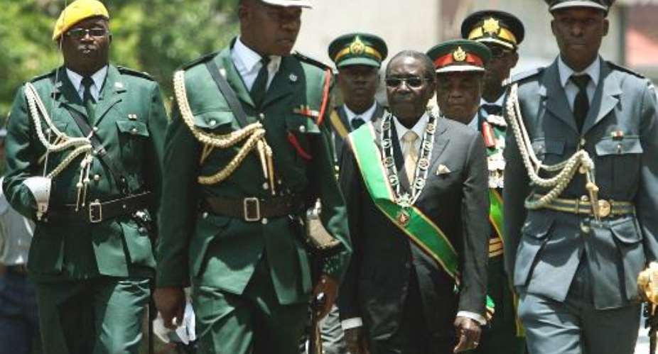 Robert Mugabe centre inspects an honor guard on October 28, 2014 during the official opening of parliament in Harare. AFP Photo  Jekesai Njikizana.  By  AFP