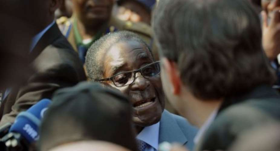Zimbabwe President Robert Mugabe C answers journalists questions after voting in Harare on July 31, 2013.  By Alexander Joe AFPFile