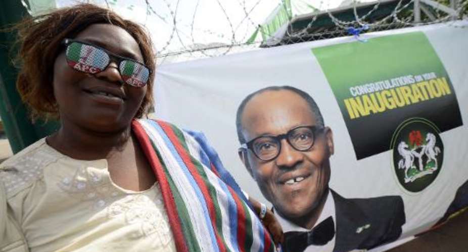 A party supporter wearing All Progressives Congress Party glasses poses with a banner for president-elect Mohammadu Buhari ahead of Friday's handover ceremony in Abuja on May 28, 2015.  By Pius Utomi Ekpei AFP