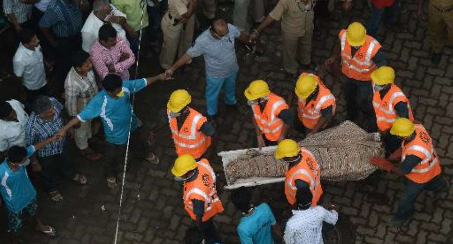 Indian personnel from the National Disaster Relief Force NDRF carry a body from the debris of a building collapse site in Mumbai on September 28, 2013.  By Punit Paranjpe AFP