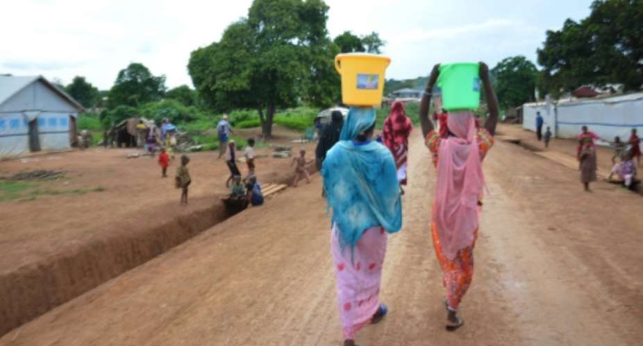 Women carry buckets of water in the streets of the Muslim area in Boda, southern Central African Republic on May 21, 2015.  By Patrick Fort AFPFile