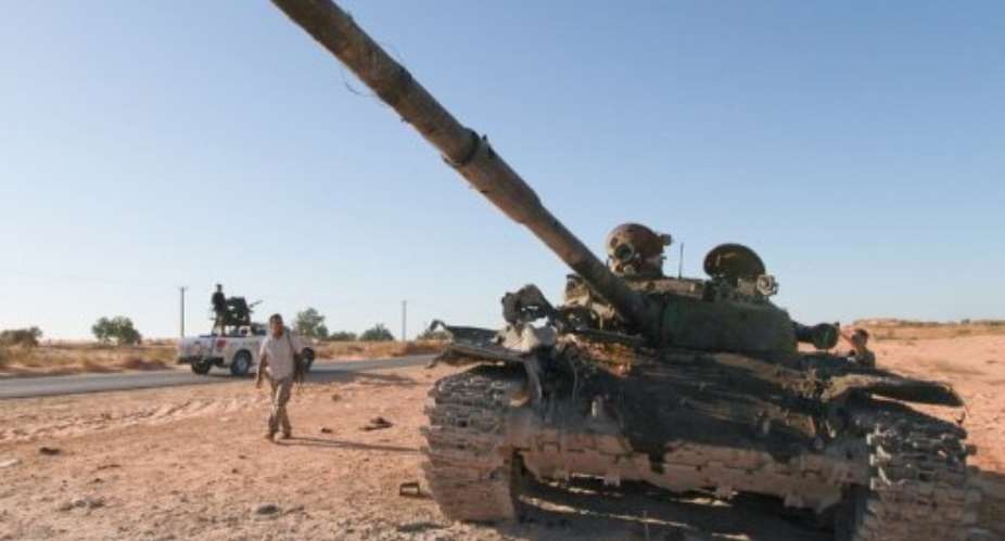 A Libyan walks past a destroyed tank, mistakenly bombed by NATO forces, killing four rebels.  By Marc Hofer (AFP)
