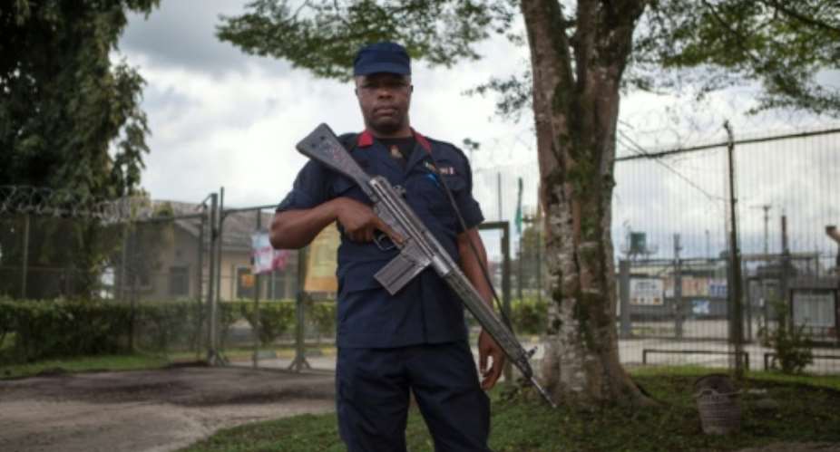 An armed security contractor for Shell guards the entrance of one of its oil facilities in Port Harcourt.  By Florian Plaucheur AFPFile