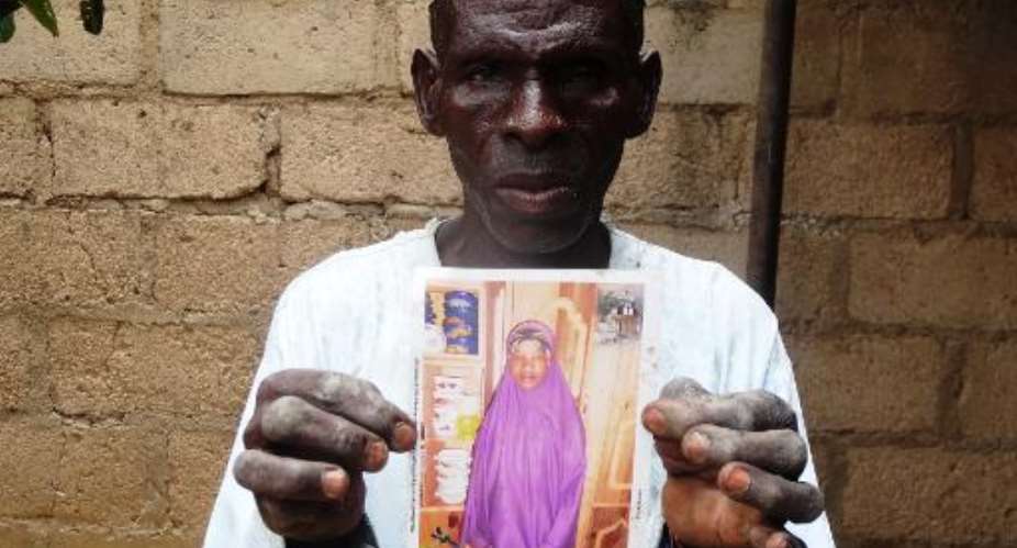 Sani Garba holds a picture of his daughter-in-law Wasila Tasi'u on August 10, 2014 inside her abandoned matrimonial home in the village of Unguwar Yansoro, outside Kano.  By Aminu Abubakar AFP