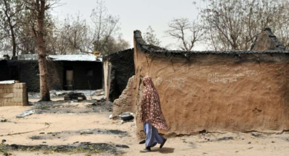A woman walks past her burned house in Gubio in Borno State, northeast Nigeria, on May 26, 2015 after an attack by Boko Haram.  By  AFPFile