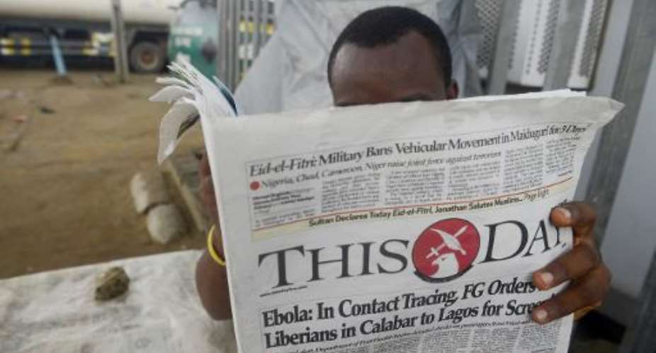 A man reads a newspaper with a headline announcing government efforts to screen for Ebola, at a newsstand in Lagos on July 27, 2014.  By Pius Utomi Ekpei AFP
