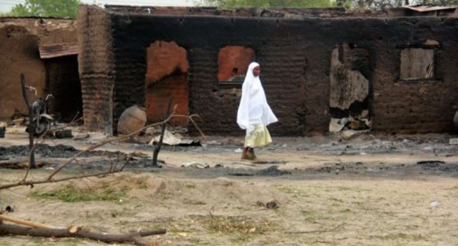 A woman walks past burnt houses in the town of Baga on April 21, 2013, after clashes between officers and Boko Haram.  By  (AFP/File)
