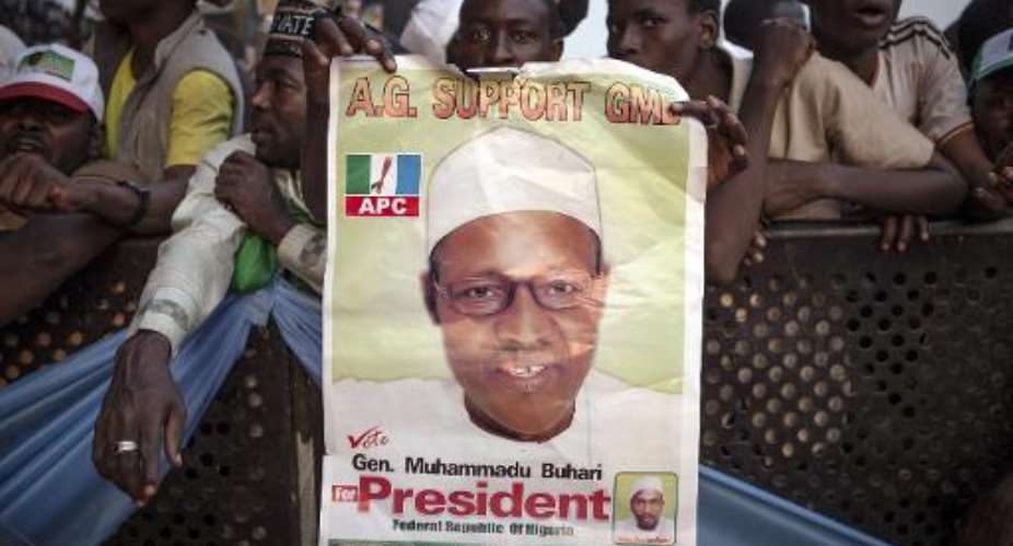A supporters of the main Nigerian opposition All Progressive Congress APC party holds a campaing poster for Muhammadu Buhari, during a rally in Kaduna on January 19, 2015.  By Florian Plaucheur AFPFile