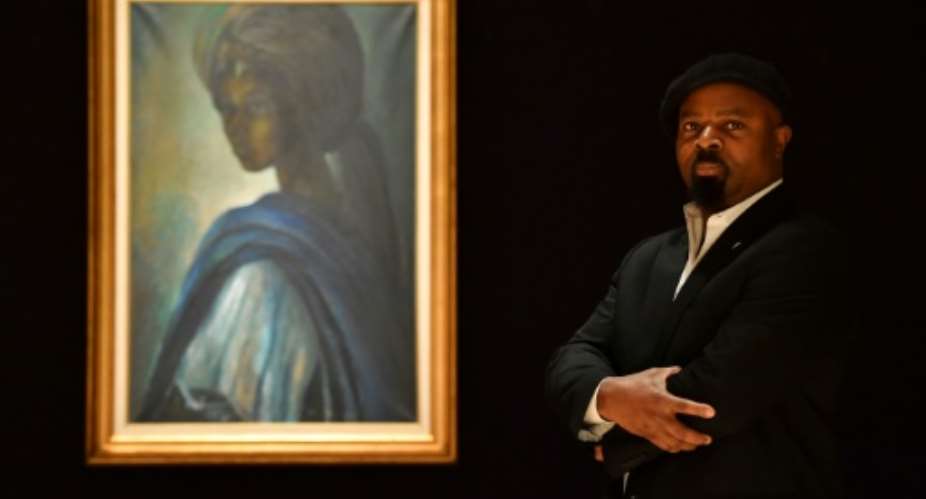 Nigerian author Ben Okri poses last year with Ben Enwonwu's 'Tutu' known as the 'African Mona Lisa'.  By BEN STANSALL AFP