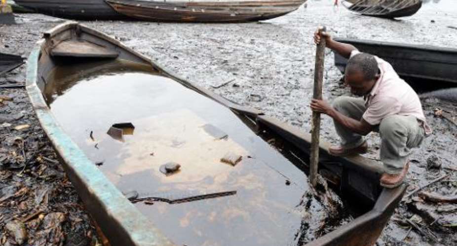 A man tries to separate crude oil from water in a boat at the Bodo waterways polluted by oil spills attributed to Shell equipment failure.  By Pius Utomi Ekpei (AFP/File)
