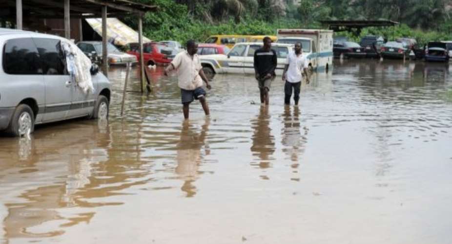 Men walk through a flooded road, beside a mechanic workshop, in the Alapere district of Lagos, in July.  By Pius Utomi Ekpei AFPFile