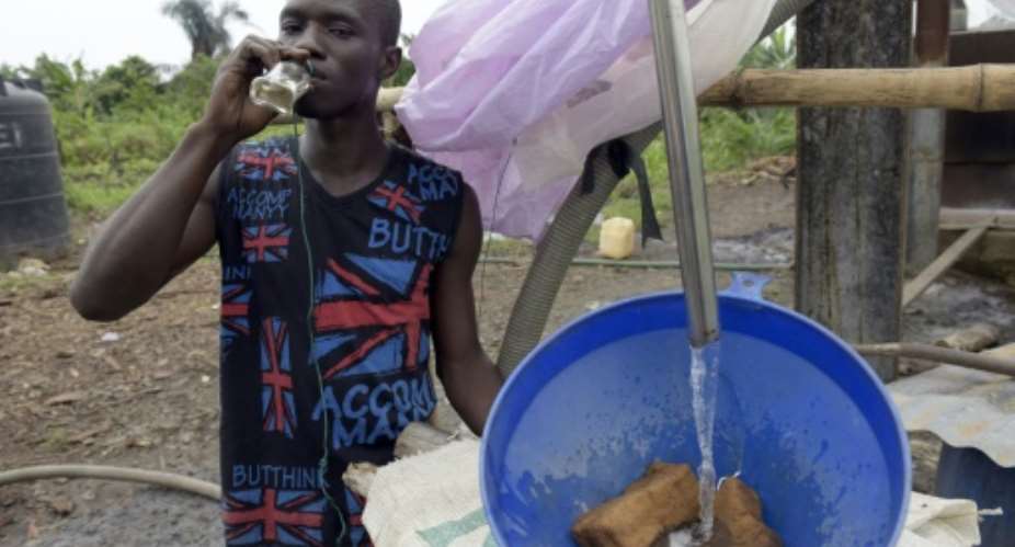 A brewer drinks locally made gin, known as ogogoro, as he filters it into a plastic drum at a factory in the Ikorodu district of Nigerias commercial capital Lagos on August 12, 2015.  By Pius Utomi Ekpei (AFP/File)