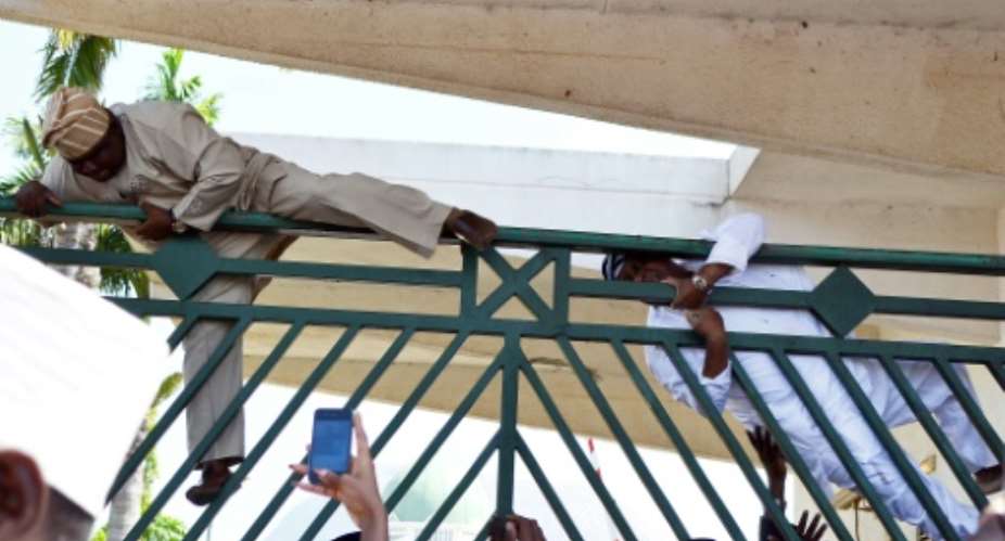 Nigerian MPs climb over the gate of parliament in 2014. Chaotic scenes often abound in the house.  By STR AFPFile
